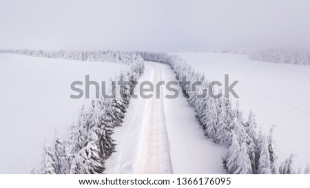 Country road going through the beautiful snow covered landscapes. Aerial view. Drone photography