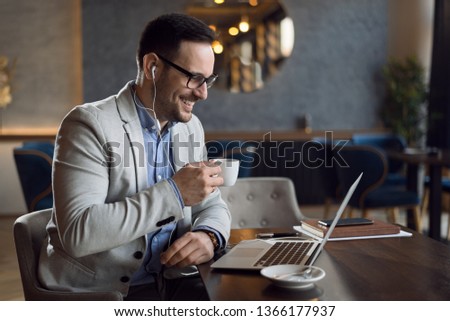 Happy young man  enjoying a cup of coffee while working on a computer.