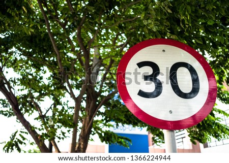 30 speed limit sign under a tree