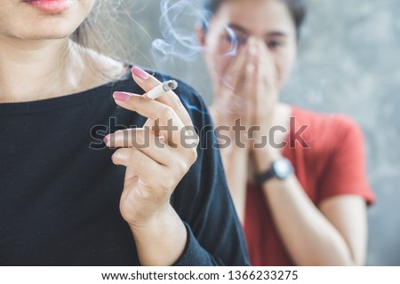 Asian woman smoking cigarette near people in family smelling pollution,passive smoking concept Royalty-Free Stock Photo #1366233275