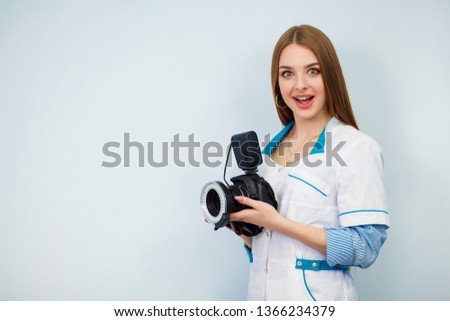 Image of a woman doctor isolated over white wall background. Dentist with a camera in hand. Copy space. Beautiful girl in a white coat