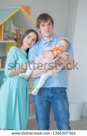 nice close-knit family of mom, dad and daughter posing in their white room