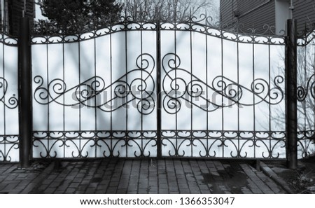 Metal gate with ornamental, iron fence, black and white.