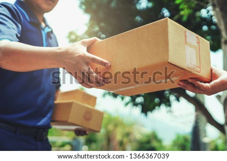 Delivery man delivering holding parcel box to customer Royalty-Free Stock Photo #1366367039