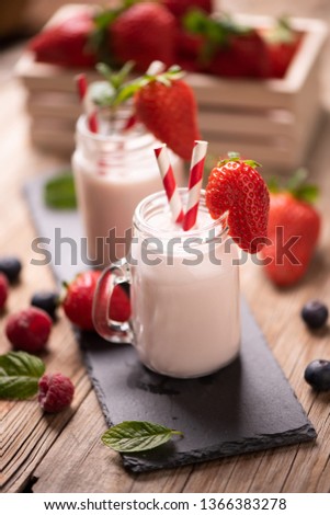 Glass of strawberry smoothie on wooden background cllose up