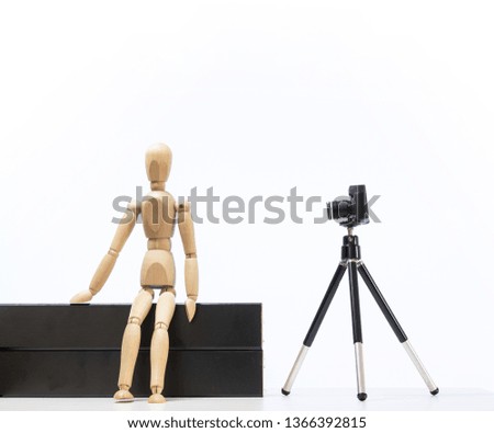Wooden man represent Photo studio with tripod, reflex camera and white background. 