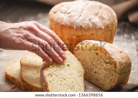 Women's hands breaking homemade natural fresh bread with a Golden crust on a napkin on an old wooden background. The concept of baking bakery products