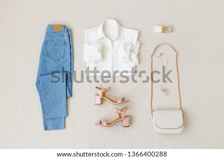 Blue jeans, white shirt, pink heeled sandals,  small cross body bag with chain strap, jewelry, accessories on beige background. Women's stylish spring summer outfit. Trendy clothes. Flat lay, top view Royalty-Free Stock Photo #1366400288