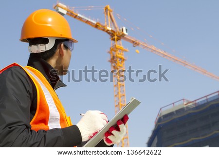 construction worker on location site with crane on the background Royalty-Free Stock Photo #136642622