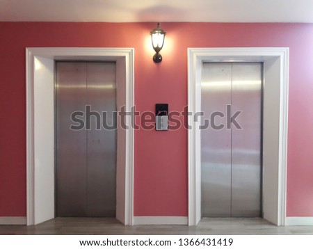 Luxury interior of elevator in the building on pink wall with bright lamp and lift button. 