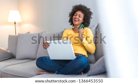 Mixed-race woman shopping on internet. Woman is holding credit card and using laptop computer. Online shopping concept. Picture showing pretty woman shopping online with credit card
