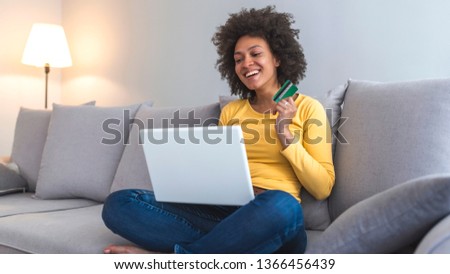 Happy woman doing online shopping at home. Beautiful mixed-race woman shopping on internet. Picture showing pretty woman shopping online with credit card. Online payment 
