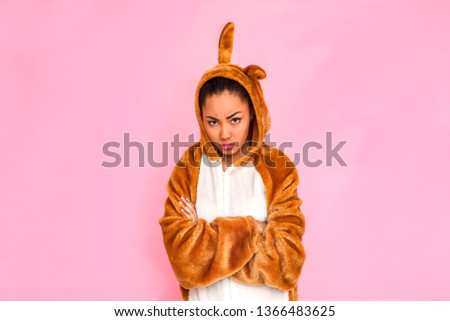 Young woman in bunny kigurumi standing isolated on pink background crossed arms looking camera angry