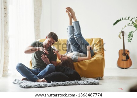With legs up. Young couple looking together at the pictures maked by camera.