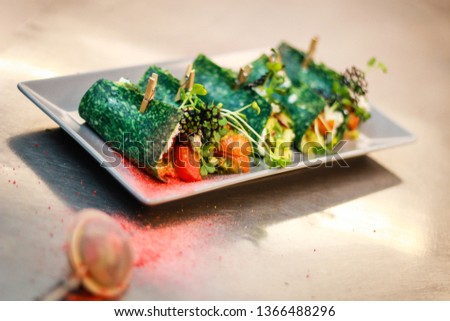 The girl's chef is preparing green crepe roles with basil cheese and stuffed. Green cheese. Cooking in the kitchen