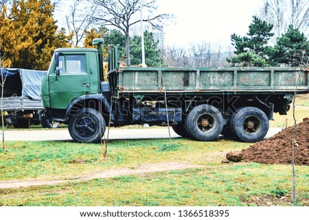 Repair work is being done in the park with the help of an old green vintage truck bringing land. Royalty-Free Stock Photo #1366518395