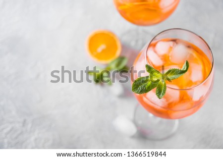 Classic Italian aperol spritz cocktail in wine glass with metal straw on light. Close up.