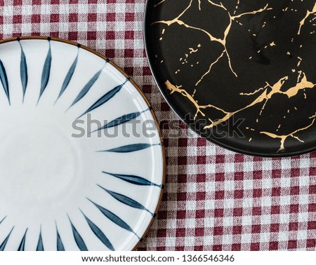 black and white flat plate rested on coaster on red patterned napkin