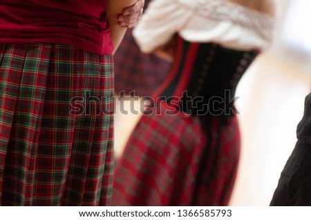 Elements of woman`s dress are made from a  squared fabric and stylized to Scottish