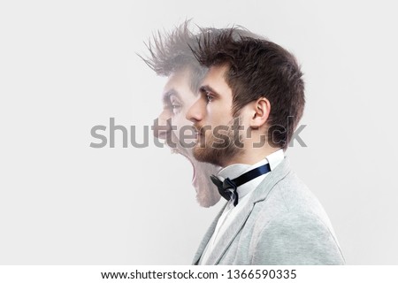 Profile side view portrait of two faced young man in calm serious and angry screaming expression. different emotion inside and outside mood of people. indoor studio shot, isolated on grey background. Royalty-Free Stock Photo #1366590335