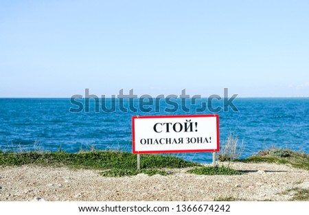 Warning sign on the background of the sea with the inscription "Stop! Danger Zone!"in Russian