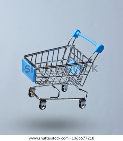 Minimalism shopping concept. Toy shopping trolley on a gray background. Photo with shadow