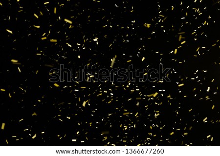 Thousands of confetti fired on air during a festival at night. Image ideal for backgrounds. Gold are the confetti in the picture. The sky as background is black