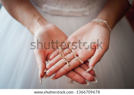 Bride holding gold christian crests in the hands