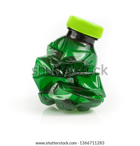 Crushed dark green plastic bottle on white background. Still-life square picture taken in studio with soft-box.