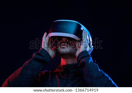 Model young man with beard in glasses of virtual reality on dark background. Augmented reality, science, future technology concept. VR. Futuristic 3d glasses with virtual projection. Neon light.