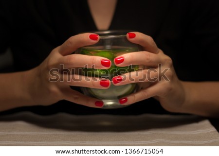 Woman hands holding a glass of mint tea on a cozy winter evening