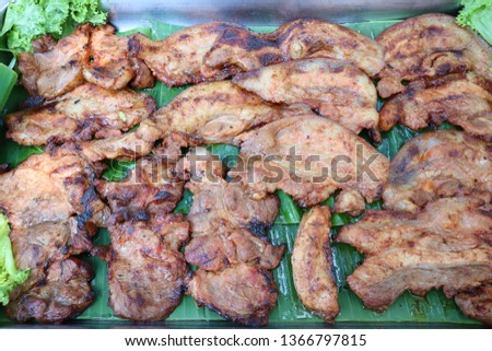 Close up, marinated pork neck, grilled herbs and vegetables placed on banana leaves, Thai style grill