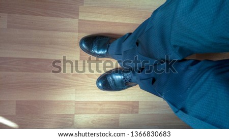 Top view of men's legs in dark checkered trousers and classic black boots standing on the wooden floor Royalty-Free Stock Photo #1366830683