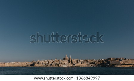 View of skyline of Valletta, Malta under blue sky, with dome of Basilica of Our Lady of Mount Carmel and tower of St Paul's Pro-Cathedral
