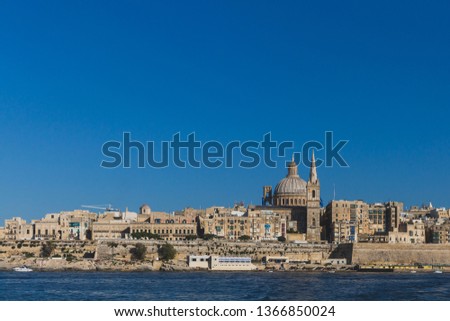 View of skyline of Valletta, Malta under blue sky, with dome of Basilica of Our Lady of Mount Carmel and tower of St Paul's Pro-Cathedral