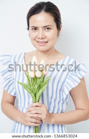 Beautiful asian woman holding bouquet of tulips on white background