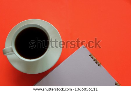 top view black coffee and notebook on orange background