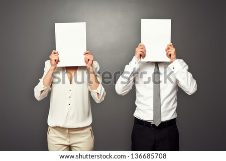man and woman hiding their faces behind white paper