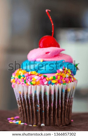 Single cupcake colorful with sprinkles and cherry on the top