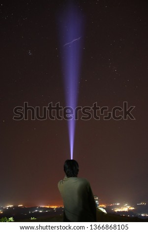 A man holding flashlight to create the beam of light. 