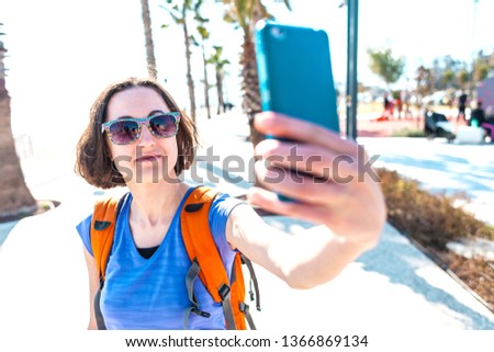 A girl takes a selfie on the waterfront. A woman walks through the resort town and takes pictures. Brunette travels around the Turkish city.