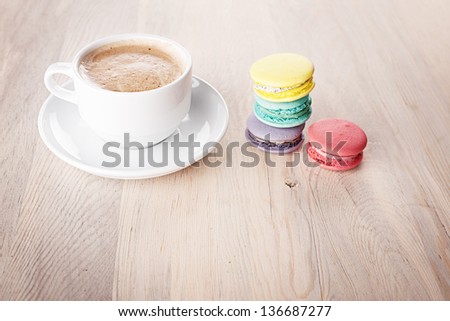 stacked macaroons and a cup of coffee on wooden table
