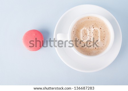 cup of coffee and a pink macaroon on blue background