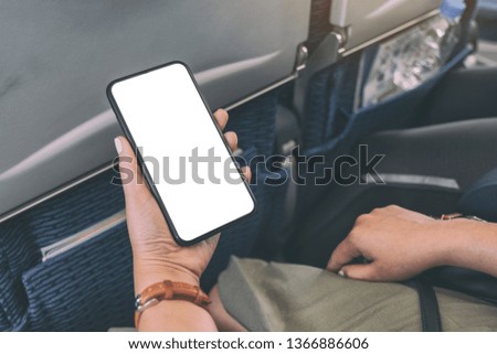 Mockup image of woman's hand holding a black smart phone with blank desktop screen in cabin