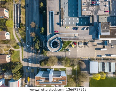 Aerial view of rooftop parking with spiral ramp for car. Street and industrial area from above.