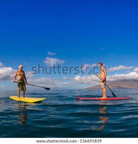 Father and son paddle boarding and exercising together