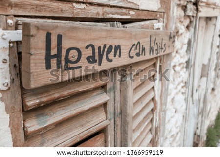 “Heaven can wait” wood board sign. Spiritual message on crafted wood shutters in picturesque central Athens.