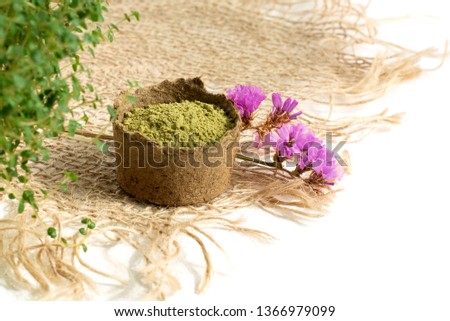 henna powder for dyeing hair and eyebrows and drawing mehendi on hands,  with green  leafs and pink flowers and sackcloth