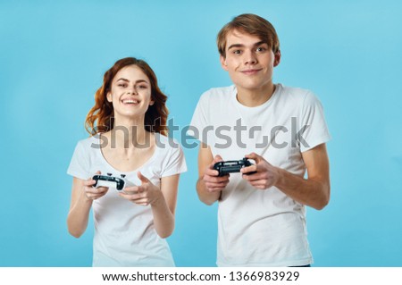 Cute young couple in white T-shirts with gamepads in the hands of a video game console game online chatting