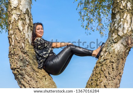 Young moluccan indian woman sitting in birch tree with blue sky